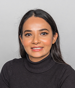Jasprit Kaur, one of the hosts, smiles gently at the camera in a portrait photo.