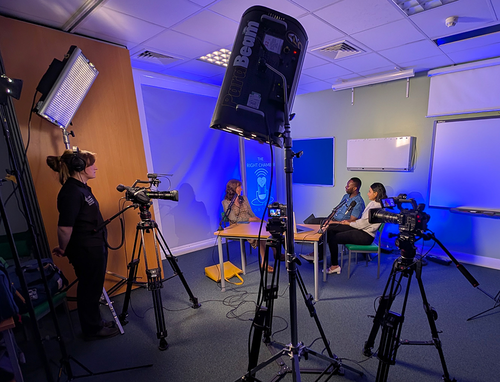 Studio setup with three people, cameras, lights ready to record podcast